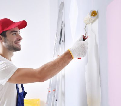 Young worker painting wall in room Young worker painting wall in room